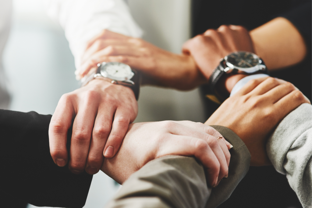 adaptacja ekspatriantów w Polsce. 5 dłoni różnych kolorów skóry trzymających się wspólnie w geście jedności