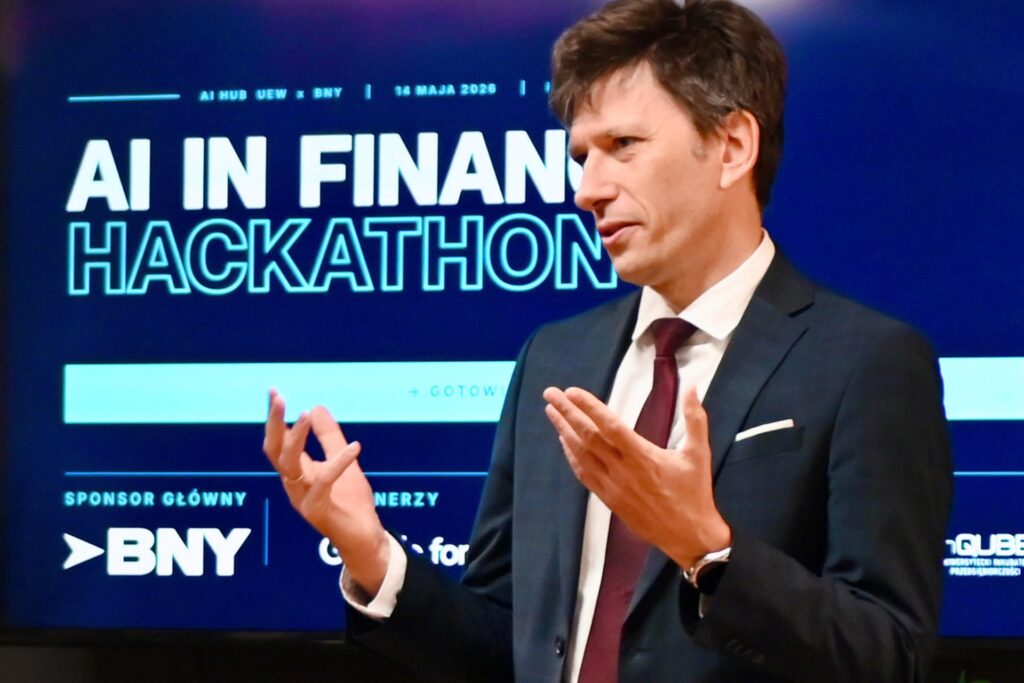 Zdjęcie z wydarzenia. W tle napis AI in Finance Hackathon. Na pierwszym planie mówca