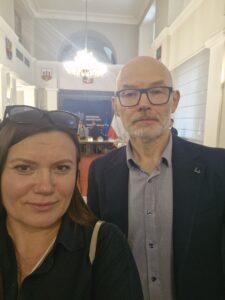 Zdjęcie mgr Ałła Witwicka-Dudek oraz dr hab. inż. Krzysztof Piontek, prof. UEW. Zdjęcie ze spotkania. W tle Sala obrad oraz baner z napisem Wojewoda Dolnośląski na granatowym tle oraz flagi - Polska i Unijna.