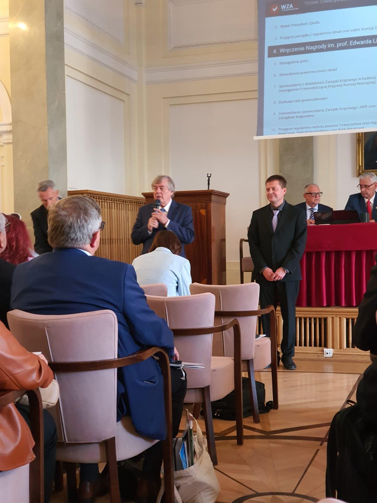 Na zdjęciu dr hab. Paweł Dobrzański przy wręczaniu nagrody PTE. Na sali obecni goście oraz przewodniczący